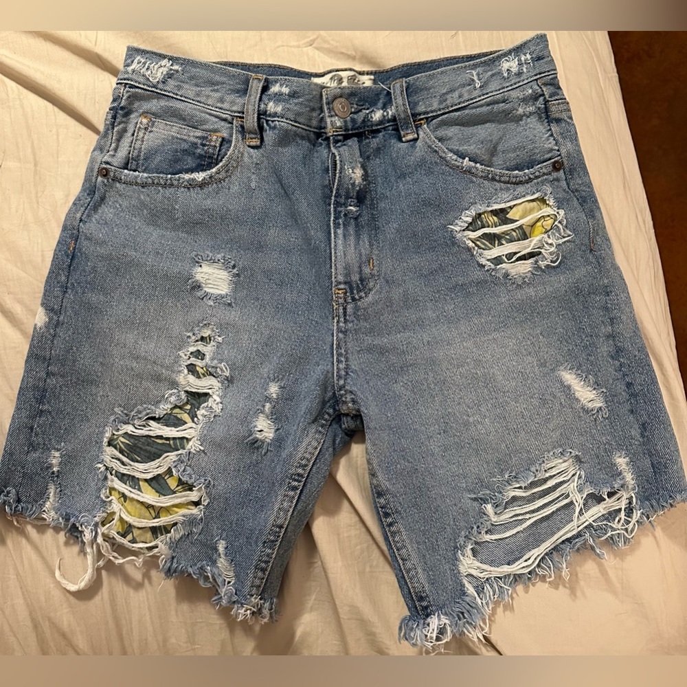 We the Free denim shorts. Frayed hem with floral details in distressed areas.